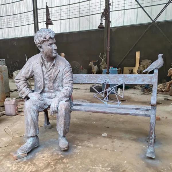 bronze statue man sitting on park bench with a bird