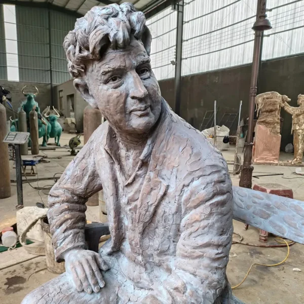 bronze statue man sitting on park bench with a bird